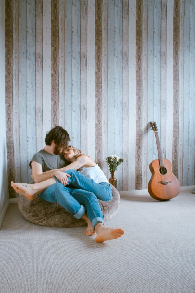 a man and woman sitting on a wall next to a guitar